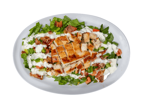 Fresh chicken Caesar salad with lettuce, bacon, and dressing on a white plate.