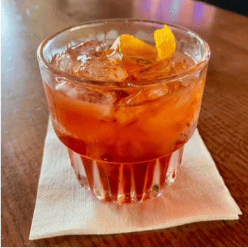 Refreshing cocktail with orange peel and ice at The Holiday Bar.