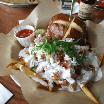 Juicy burger with fries, bacon, and fresh greens at The Holiday Bar.