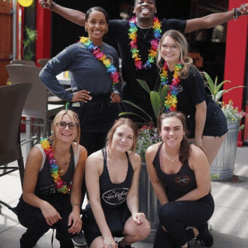 Group of diverse women celebrating at The Holiday Bar with leis and smiles.