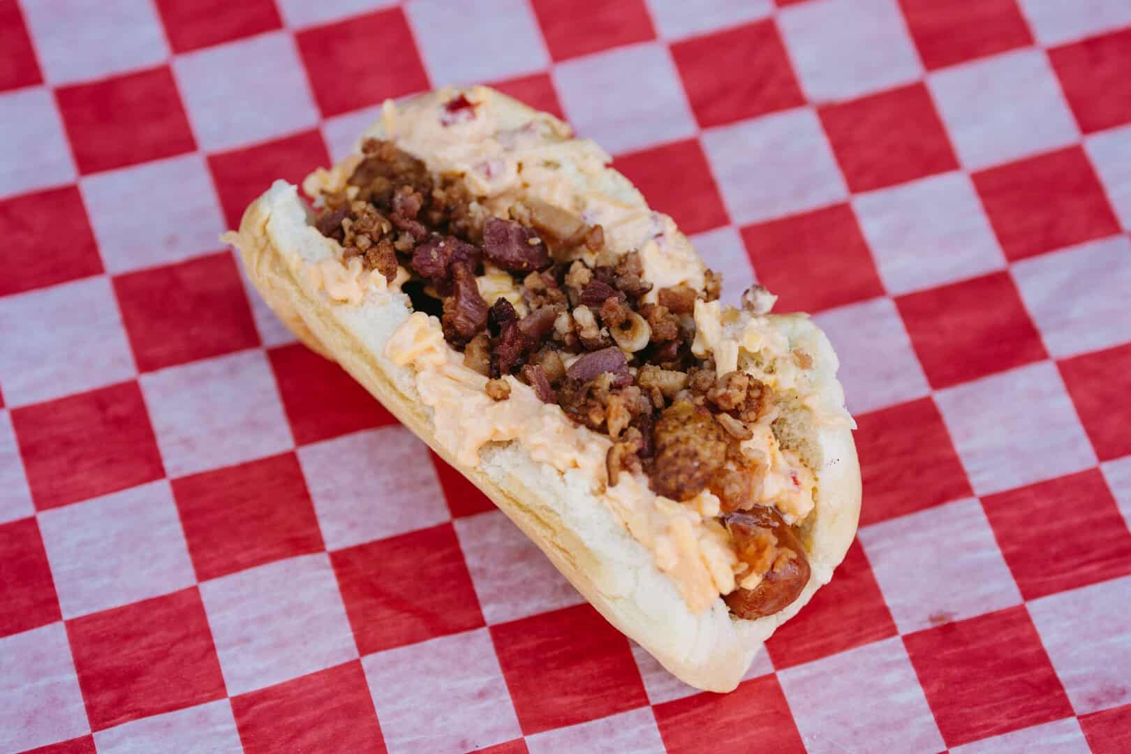 Delicious hot dog with ground beef, bacon, and cheese on a bun.