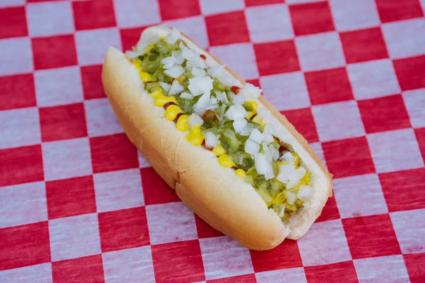 Hot dog with relish, onions, and mustard on a bun.