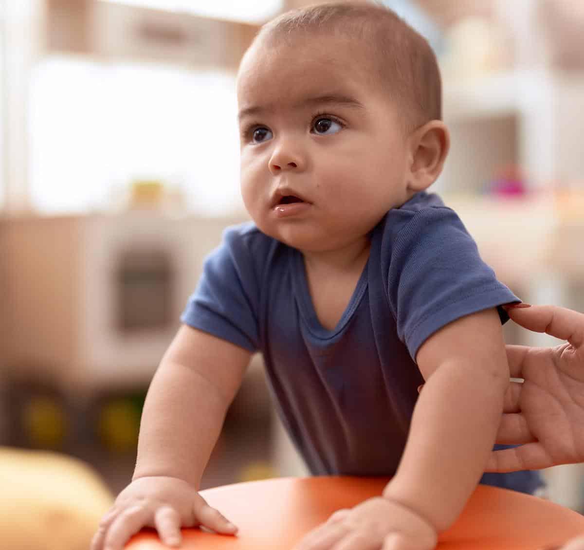 baby in blue shirt standing with ball