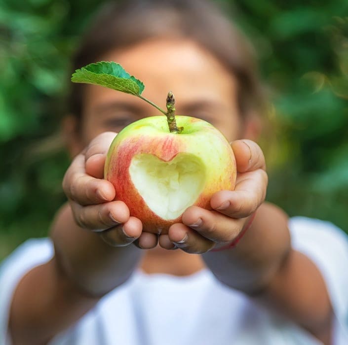 girl holding apple with heart shaped bite