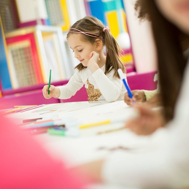 group of kindergarten students writing at table
