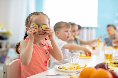 young girl playing with cucumber slices