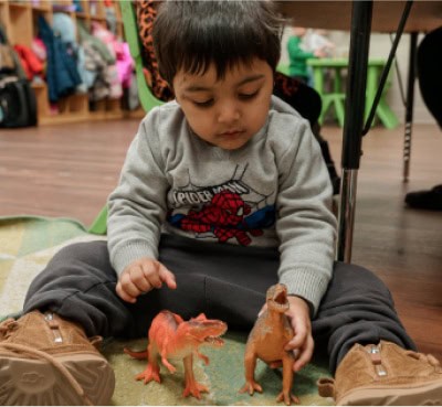 young preschooler playing with dinosaur toys