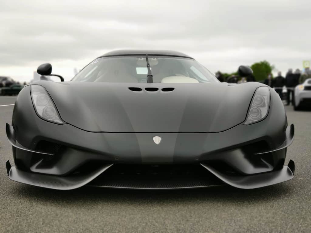 Mattsort Koenigssegg regera sportsvogn set forfra på en grå dag.