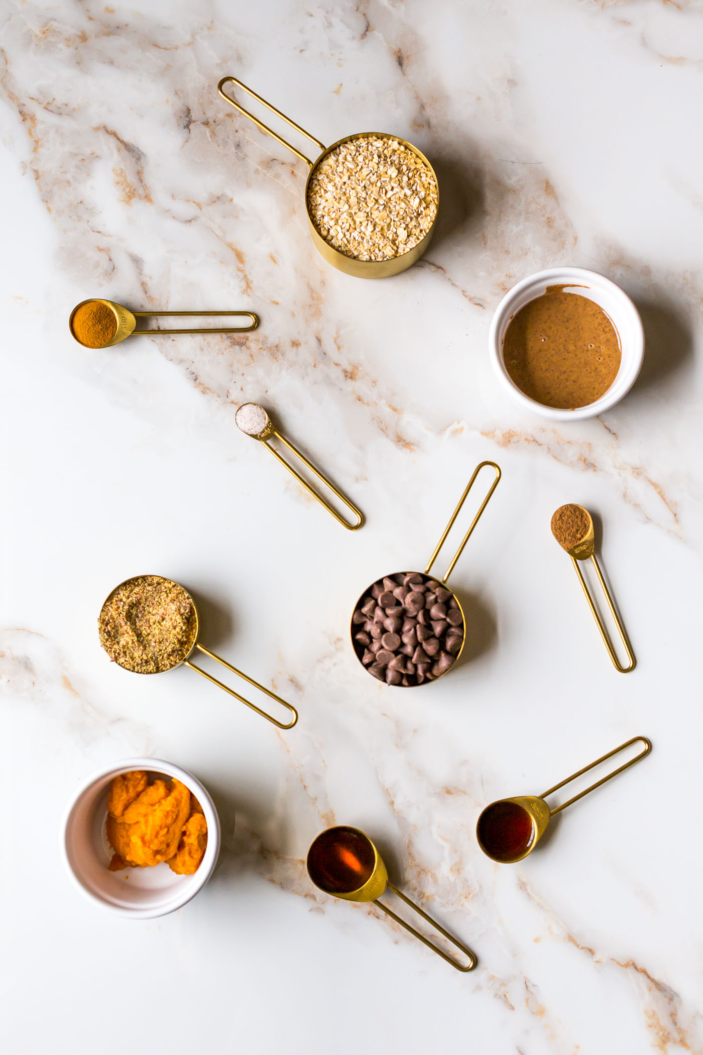 Ingredients in measuring cups and measuring spoons of no bake pumpkin energy bites 