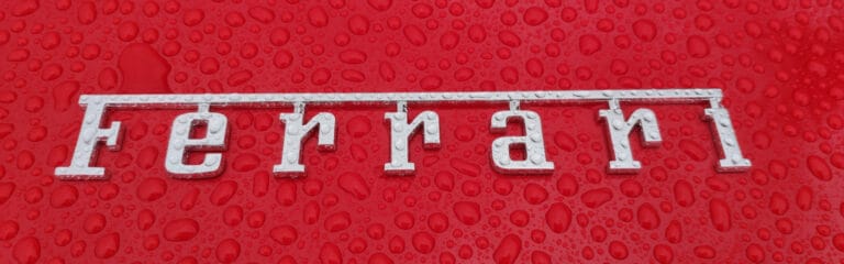 Ferrari-logo på en våd, rød overflade med vanddråber.