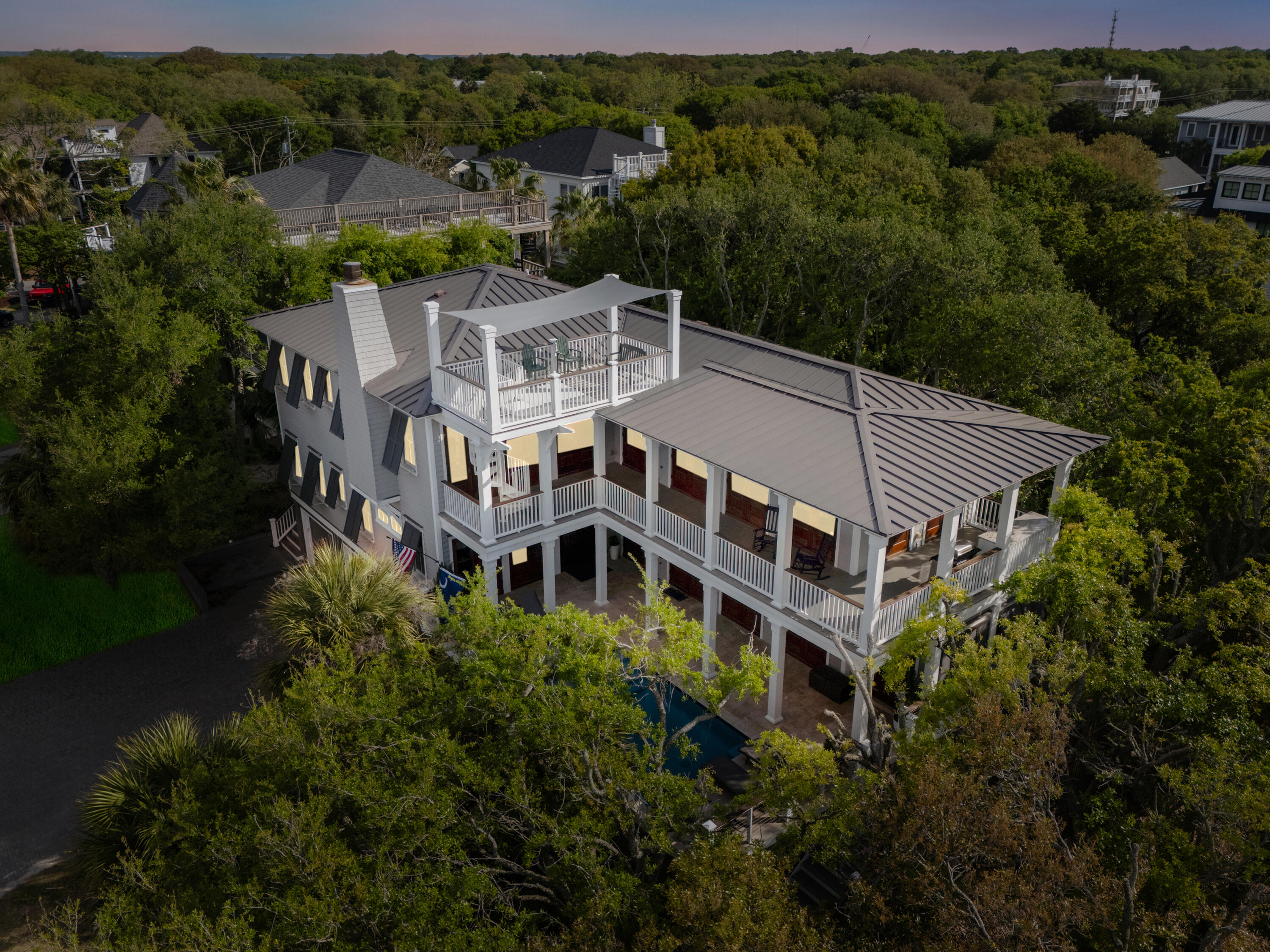 Live at the Beach in this custom built beach house by esteemed builder, Sheppard Construction. Located across the street from the pristine beaches of Isle of Palms. Nestled among live oak trees, this 6 bedroom, 5 bathroom home was designed to take full advantage of the sea breezes, natural light, and scenic views. Designed to maximize privacy, the elevated floor plan offers indoor/outdoor living through the 18 sets of Mahogany French doors leading to the elevated pool deck and second story porch. Upon entering  this reverse floor plan home, you'll find two ensuite bedrooms. 1 has a queen bed, a walk-in closet with a custom closet system, private bathroom w/  drop in tub and tile surround. Bedroom 2 has a king bed,  w/ drop-in tub with tiled surround that also connects to the hallway.Down the hall is bedroom 3 which has 2 sets of bunk beds. This floor also features the media room, with built-in speakers, built-in media station and a mini fridge. Additionally, there is a Primary suite on the first floor. This space offers a walk-in closet with custom organizers, a secondary reach-in closet, and a massive bathroom with a drop-in bubbler tub w/ marble surround, dual countertops, marble shower, and separate water closet. The primary has a private lounge area within, as well as all access doors leading to pool and deck. With an elevated pool you will have ultimate privacy while enjoying the summer sun with travertine surround and outdoor speaker system. 

The second floor boasts a large open living space with a real wood burning fireplace, concrete hearth, built-in ceiling speakers, and doors leading to the upper deck. The designer inspired Chef's kitchen offers Sub Zero side by side refrigerator, Wolf gas range with double ovens, wine fridge, ice maker, Bosch dishwasher, a coffee station, built-in microwave, built in glass front cabinetry, marble countertops, and a Wolf vent hood and bar sink in the island. The laundry is conveniently connected to the kitchen with custom built in storage. The dining room is adjacent to the kitchen with ample room for all of your guests with plenty of room left for an additional seating area at the front of the home. This floor also has 2 ensuite bedrooms. Bedroom 4 has a king bed, a reach-in closet and a bathroom w/ a tiled shower that connects to the hallway. Bedroom 5 has a queen bed, a walk-in-closet and a bathroom with a drop in tub and tile surround. 

As an added bonus a spiral staircase leads to a "widow's walk" rooftop porch offering a breathtaking panoramic view of the Atlantic ocean beneath a stretched sunshade. The side yard has a private gated entrance and boasts a firepit and ample space to enjoy those salt air breezes. 

Some of the many additional notable features of the home include 3 car garage plus room for toys, golf carts, ping pong table etc, 3 stop elevator, central vacuum, outdoor shower in garage, large owners' closet in garage and main house, irrigation system, Bahama shutters, house alarm system, crown molding throughout, 9ft+ height ceiling, site finished hardwood flooring and more! Side entry driveway located on 33rd Ave. Located on the north end of the island, this home is a short golf ride to the IOP Marina, Rec Department, shopping, and dining.