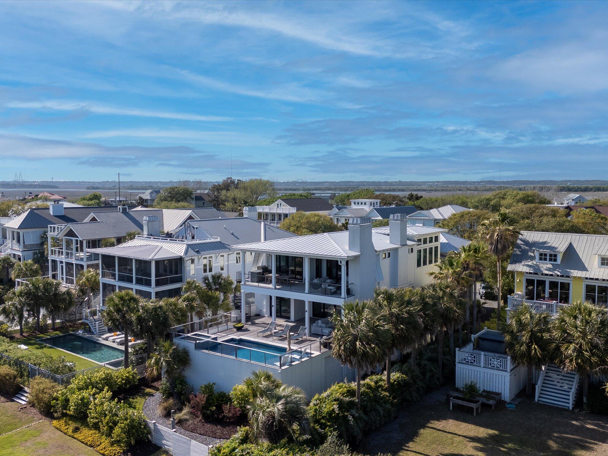 Highly anticipated and undeniably worth it--you've been patiently waiting for a home like this, and it's finally here. This is the one!  Ideally situated just steps from the beach, on Isle of Palms most coveted enclave, known as ''Millionaire's Row.'' This architecturally striking 5-bedroom, 5.5-bath residence captures the essence of a Miami Beach resort infused with the sleek sophistication of a New York City penthouse. Spanning 4,957 square feet on a .29-acre lot, the home offers peaceful ocean views from the rear while preserving a rare sense of privacy and coastal calm. This residence has been masterfully reimagined for elevated living--now showcasing a show-stopping kitchen renovation that defines luxury in both form and function. At its heart, the gourmet kitchen is a masterclass indesign and function,  featuring ceiling-height custom cabinetry and quartzite countertops. Equipped with Thermador's premier appliance suite including: Fuel Range with 6 Burners & Griddle, separate column refrigerator and freezer, panel ready wine refrigerator, and built-in dishwasher. A massive island anchors the space, perfect for entertaining and adjacent to the dining area. Discreetly tucked behind dual pocket doors, the beautifully appointed scullery enhances functionality with expansive countertops, high-gloss custom cabinetry, a Bosch wall oven, a Thermador refrigerator/freezer, a Thermador dishwasher, plus an additional sink for effortless prep and cleanup.

Designed with a reverse floor plan to take advantage of elevated coastal views and natural light throughout, this home boasts wide-plank European white oak flooring, minimalist reglet baseboards and trim, and curated lighting selections throughout. The upper level features the main living space, kitchen, scullery, powder room with new cabinets, and the primary suiteeach space thoughtfully arranged to maximize both comfort and flow.

Off the living area, wide sliding doors open onto an expansive covered deck where a floating hearth gas fireplace, built-in grill with countertop workspace, and integrated television invite al fresco living at its finest. This outdoor living and dining area also enjoys serene views overlooking the pool below.

In the primary suite, elegant cove lighting adds a soft, ambient glow and modern architectural detail to the ceiling design. The spa-inspired primary bath is an oasis unto itselffeaturing updated cabinetry, floor-to-ceiling tile, dual vanities, a zero-entry walk-in shower, a luxurious Victoria & Albert soaking tub, backlit mirrors, and a spacious dual custom closet with a washer/dryer within.

The home's grand entry foyeranchored by a custom two-story glass chandelier and a striking glass-railed staircasesets the stage for the level below, where refined design and livable luxury converge. A sophisticated lounge with wet bar, floating shelves, and an HD wall-mounted display offers the perfect retreat or gathering space. 

Glass sliders lead to a second covered terrace that mirrors the finishes and comforts of the upper deckcomplete with a gas fireplace, integrated television, and a lounge-style seating area. Just beyond, the resort-style pool and spa invite relaxation with an in-water sun shelf and umbrella perch. A curved spiral staircase connects the upper and lower decks, allowing for easy movement between the levels without sacrificing privacy or style. 

This floor hosts three guest bedrooms, each with its own ensuite bath featuring high-end tile work and floating vanities, along with a full laundry room for added everyday convenience. The fourth guest ensuite is located in a private retreat over the garage, connected via a skywalk and offering the ultimate in privacy and flexibility. With vaulted ceilings, a built-in wet bar, private balcony, and dedicated exterior entrance, it's an ideal haven for extended guests or additional living space.

State-of-the-art systems include Elan smart home automation, home audio in all main spaces, low-profile LED recessed lighting, cove lighting (primary and rear bedroom), three high-efficiency heat pumps, and spray foam insulation for optimal comfort and energy performance. The oversized dual garage features room for 5 cars, a separate storage room, an outdoor shower and a motorized lift storage. The professionally landscaped yard, new fencing, newer interior and exterior paint, and an elevator that accesses all levels, round out this extraordinary offering. The meticulously executed enhancements totaling over $200,000 have elevated the architectural integrity and material sophistication of this masterpiece.

This is not just a home it's a lifestyle, where modern luxury and coastal serenity coexist seamlessly. Most people wait all year to go on vacation here, you wake up and live it every single day. House is currently on short term rental as one of the premier properties on Isle of Palms.