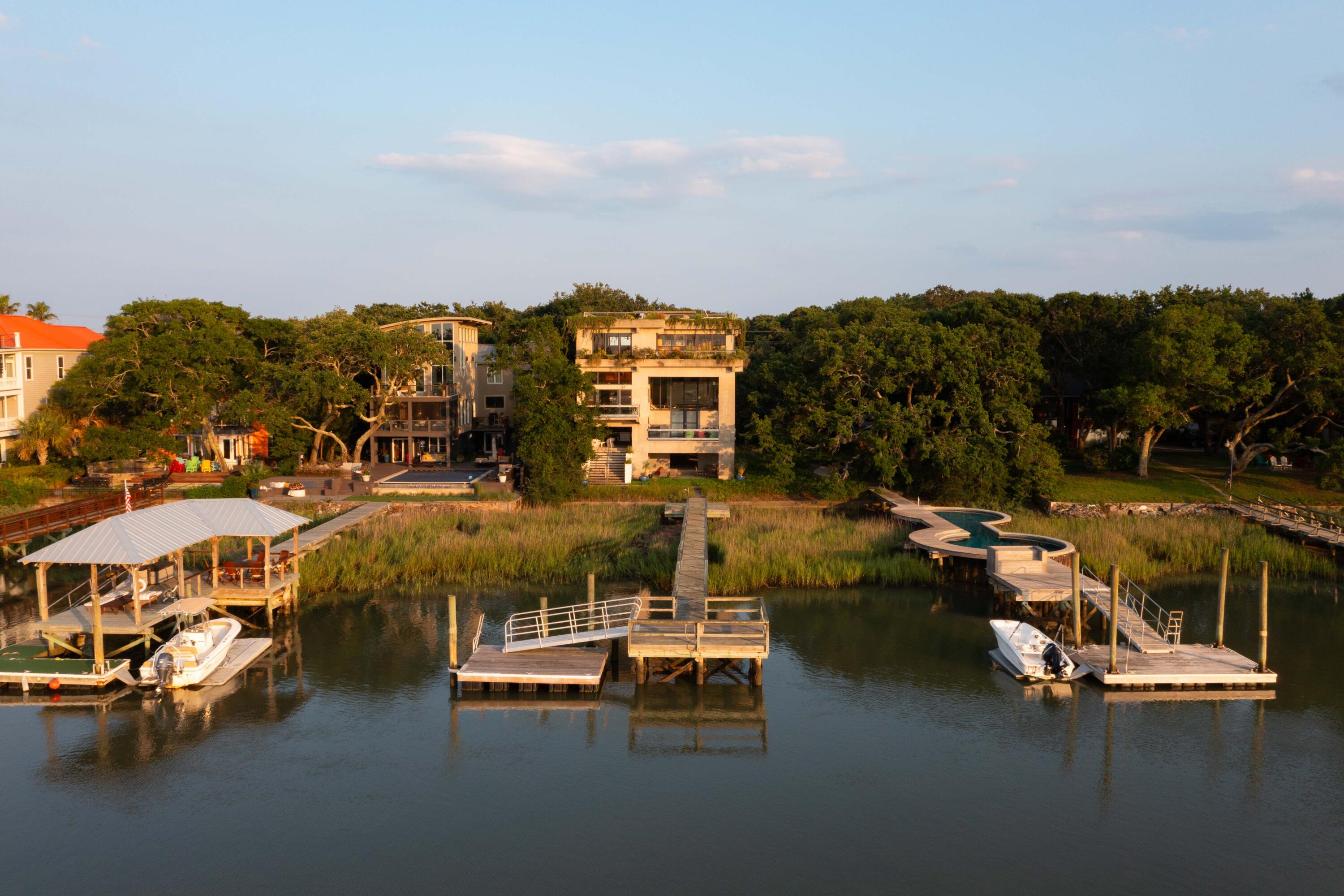 Settle into the gentle rhythms of Lowcountry waterfront living in this modern masterpiece on Isle of Palms. Every detail of this magnificent property was a thoughtful collaboration between the owners and architect Pierre Strauch during a multi-year design and build process. The striking exterior conveys the strength and resilience of the concrete and steel structure, while also showing the home's softer side with enormous panels of glass and built-in planters allowing plants to cascade along sections of exterior walls. The transition from exterior to interior space is gradual and welcoming, with a cozy foyer setting the tone with a warm and comforting enclosure, before moving into more grand areas. Custom designed windows from Crittall in the UK, bring the beauty of the waterway and marsh into full view. A variety of wood types were meticulously cut and positioned by master craftsmen to add visual warmth and texture to every room. Structural steel painted with high gloss automotive grade paint and colored glazed tiles offer bright accents and visual surprises. Throughout the home, every available space was captured for creative storage solutions masked by custom woodwork. Ample outdoor spaces, including a large roof terrace, provide opportunities for al fresco living and dining immersed in Lowcountry natural beauty. A short dock connects you to the freedom of deepwater access along Hamlin Creek, a short boat ride into the Intracoastal Waterway. The symphony of details that make this home so special could fill a book...This is truly a property that needs to be toured to be fully appreciated.