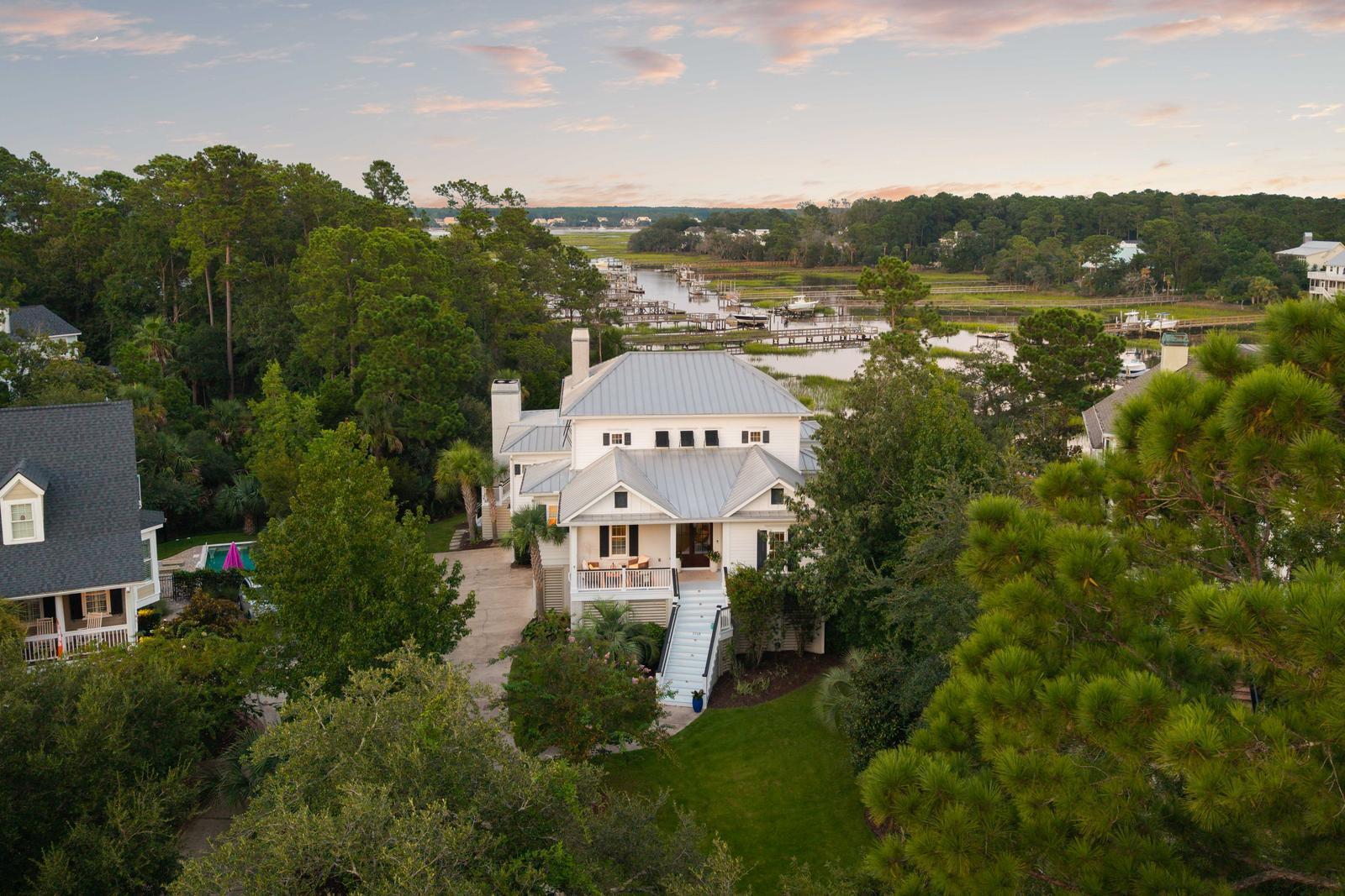 Truly Breathtaking! This luxurious waterfront home is thoughtfully designed and built to embrace the essence of Lowcountry living. Nestled on Darrell Creek--a scenic offshoot of the Wando River--this residence features its own private dock for ultimate coastal enjoyment. Located in the highly sought-after Masonborough section of the Park West community, it offers the perfect blend of elegance, comfort, and lifestyle. Enjoy sweeping, picturesque views of the landscape, vibrant sunrises, and abundant wildlife from every level of this exceptional home. From the moment you enter, your eyes are drawn to the water, framed perfectly by large, east-facing windows and doors that flood the high-ceilinged interior with natural light. The open and spacious floor plan is ideal for entertainingwith central living areas on the main floor that seamlessly connect to a private dining room, a cozy breakfast nook, and a dedicated office space. Each of these thoughtfully designed rooms offers stunning views of Lowcountry waterways including Darrel Creek and the Wando River.
Expansive porches with soaring ceilings extend the living space outdoors, crafted for year-round enjoyment. Whether you're dining al fresco, grilling with friends, or simply relaxing poolside, these porches offer the perfect setting. Two wood-burning fireplaces add warmth and charm, making this outdoor retreat a cozy haven no matter the season.
The first floor features three well-appointed bedrooms, each thoughtfully spaced for privacy and comfort. One guest bedroom includes its own en-suite bathroom, while the other two share a Jack-and-Jill bath, complete with separate vanity areas. Soft wool carpeting adds warmth and comfort throughout these rooms. A conveniently located powder room and laundry room are also found on this level.
Upstairs, you'll find a truly luxurious retreat. The expansive primary suite includes a generous sitting area, dual walk-in closets, and a beautifully designed master bathroom with a double vanity and a freestanding soaking tub. Just off the suite, a private river-facing deck offers sweeping viewsan ideal spot to begin or end your day. Completing the upper level is a versatile loft space, perfect for a home office, gym, or relaxation area.
The ground level is designed for both relaxation and recreation, featuring a spacious pool area perfect for entertaining. A shaded outdoor living space includes a cozy fireplace and TV setup, offering a cool retreat from the sun without sacrificing comfort or connection. An exterior shower adds convenienceideal for rinsing off after a day on the water before taking a dip in the pool. Experience the best of community living with the added bonus of a fully private backyard. 
The home also includes a three-bay garage with a full bath and ample room to accommodate a boat, golf cart, or additional vehicles. Thoughtfully designed with functionality in mind, the garage includes multiple storage areas, an elevator shaft, and Tesla charging capability. Additional features such as a whole-house water filtration and mosquito misting system add comfort and peace of mind to this exceptional coastal property.