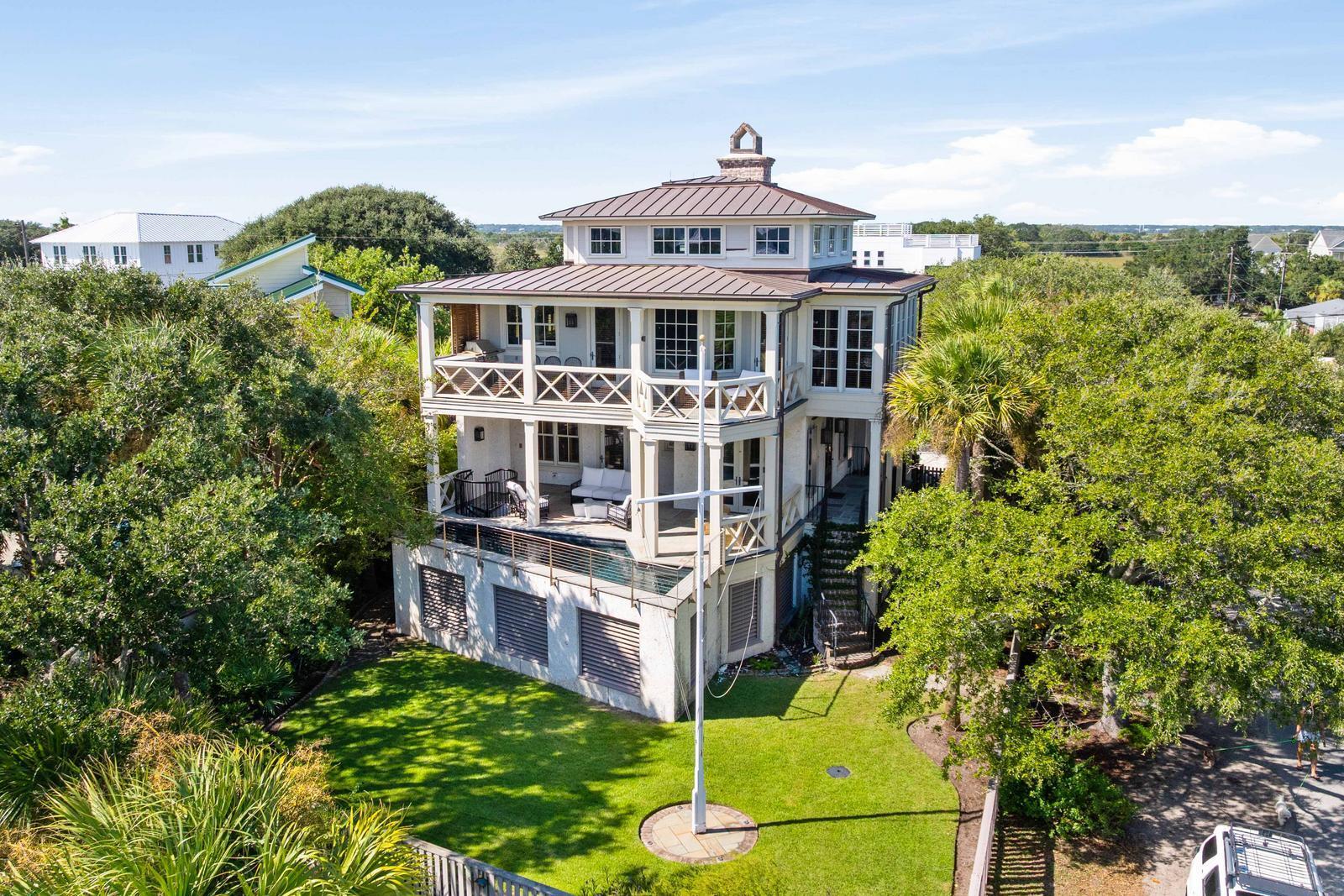 This custom-built Isle of Palms residence offers the best in coastal luxury--combining elegant design, high-end craftsmanship, and unbeatable proximity to the beach. Located just one block from the ocean, this elevated home showcases light-filled living spaces, spacious bedroom suites, luxury finishes, and exceptional outdoor areas including multiple covered porches and a private elevated pool.Inside, every detail reflects superior craftsmanship and thoughtful design. Reclaimed heart pine floors, exposed beams, cypress ceilings, Honduran cedar doors with Baldwin hardware, Italian marble and soapstone counters, and custom cypress cabinetry set a refined tone throughout. Additional highlights include a Waupaca 4-stop elevator, Sonos integrated audio/video system, and Lutron lighting.The reverse floor plan positions the main living spaces on the second level to maximize sweeping views of the Atlantic Ocean, Charleston Harbor, and Hamlin Creek. Walls of windows and vaulted ceilings fill the living, dining, and kitchen areas with natural light. The chef's kitchen is a true showpiece with marble countertops, high-end appliances (Wolf, Sub-Zero, Miele, and GE), and an adjoining custom pantry. A covered porch extends from the living area and features an outdoor kitchen with built-in gas grill and cooktop, perfect for entertaining.

The spacious primary suite offers a serene retreat with private porch access, walk-in closet, and a luxurious en -suite bath featuring marble counters, cypress cabinetry, a Bain Ultra soaking tub, tiled shower, and Myson towel warmers. Three additional en-suite bedrooms on the first floor each open to a covered porch, providing privacy and comfort for family or guests.

The top-level media room includes a wet bar, fireplace, and porch with panoramic views of the ocean, Ravenel Bridge, and surrounding marshes. The elevated pool accessed from the first-floor porch creates a private oasis surrounded by lush, professionally landscaped grounds with camellias, hydrangeas, oleanders, Palmettos, and live oaks.

A spacious garage offers ample parking and storage. Several restaurants are within short walking, biking or carting distance away on Front Beach IOP & on Sullivan's Island. With its combination of luxury finishes, ocean views, and prime Isle of Palms location, this home epitomizes relaxed coastal sophistication.
