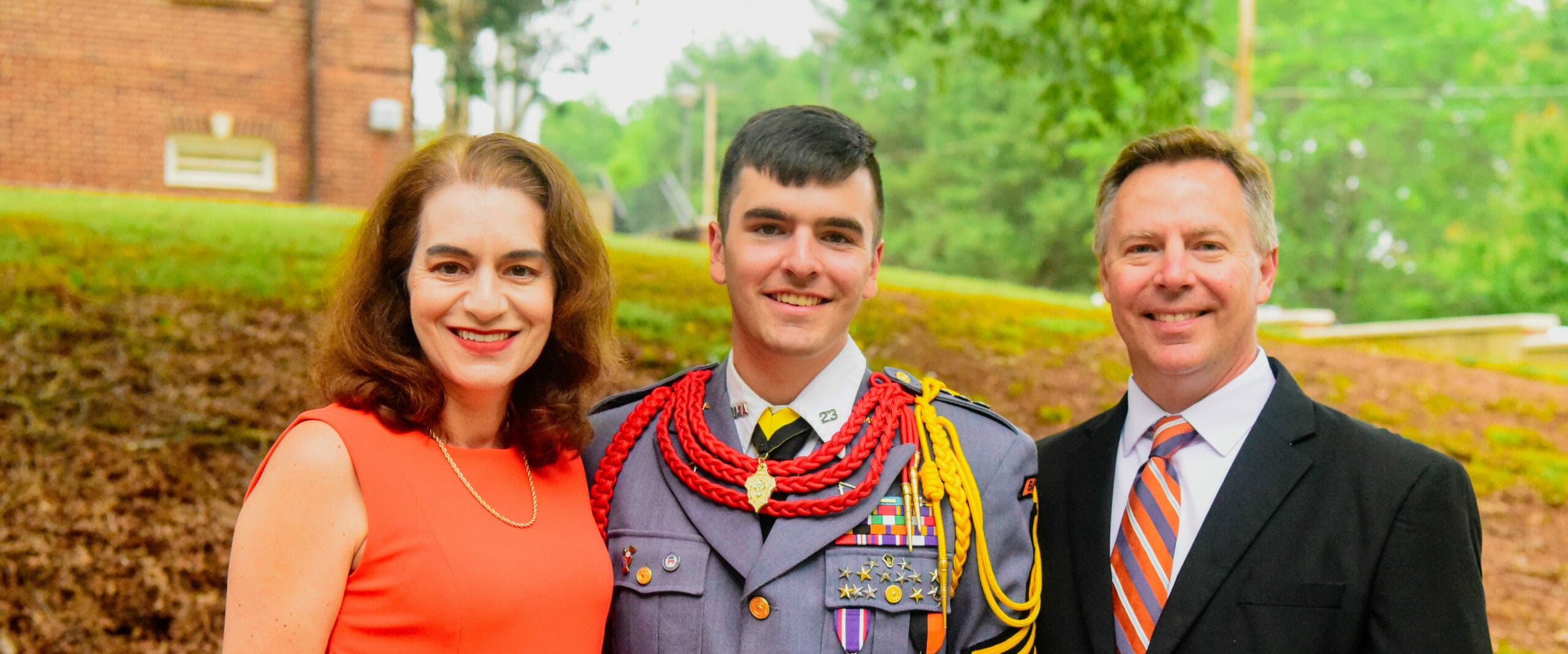 Cadet posing with his parents after graduation smiling at the viewer.