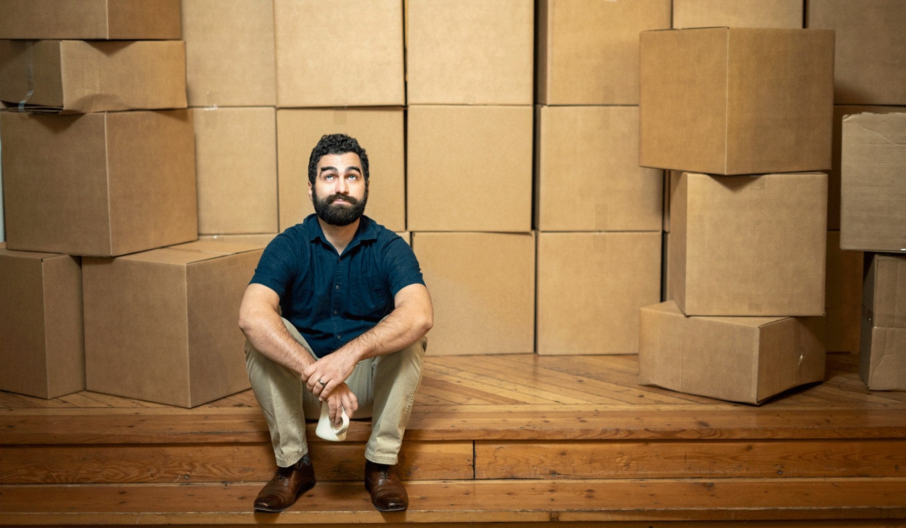 white man in blue polo in front of cardboard boxes