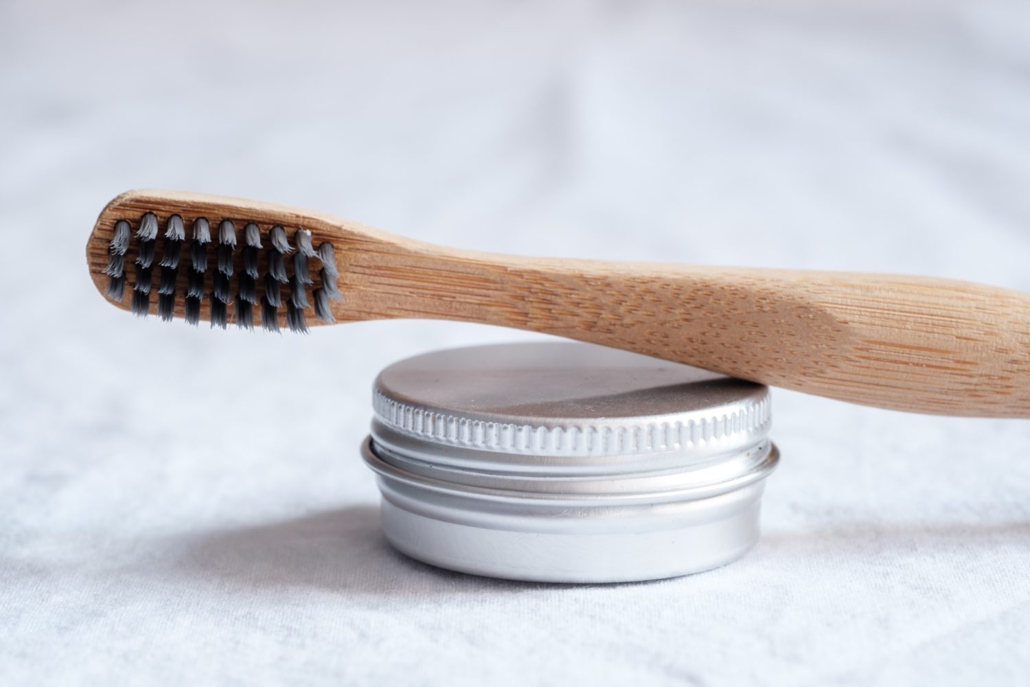 bamboo toothbrush leaning on top of small tin can