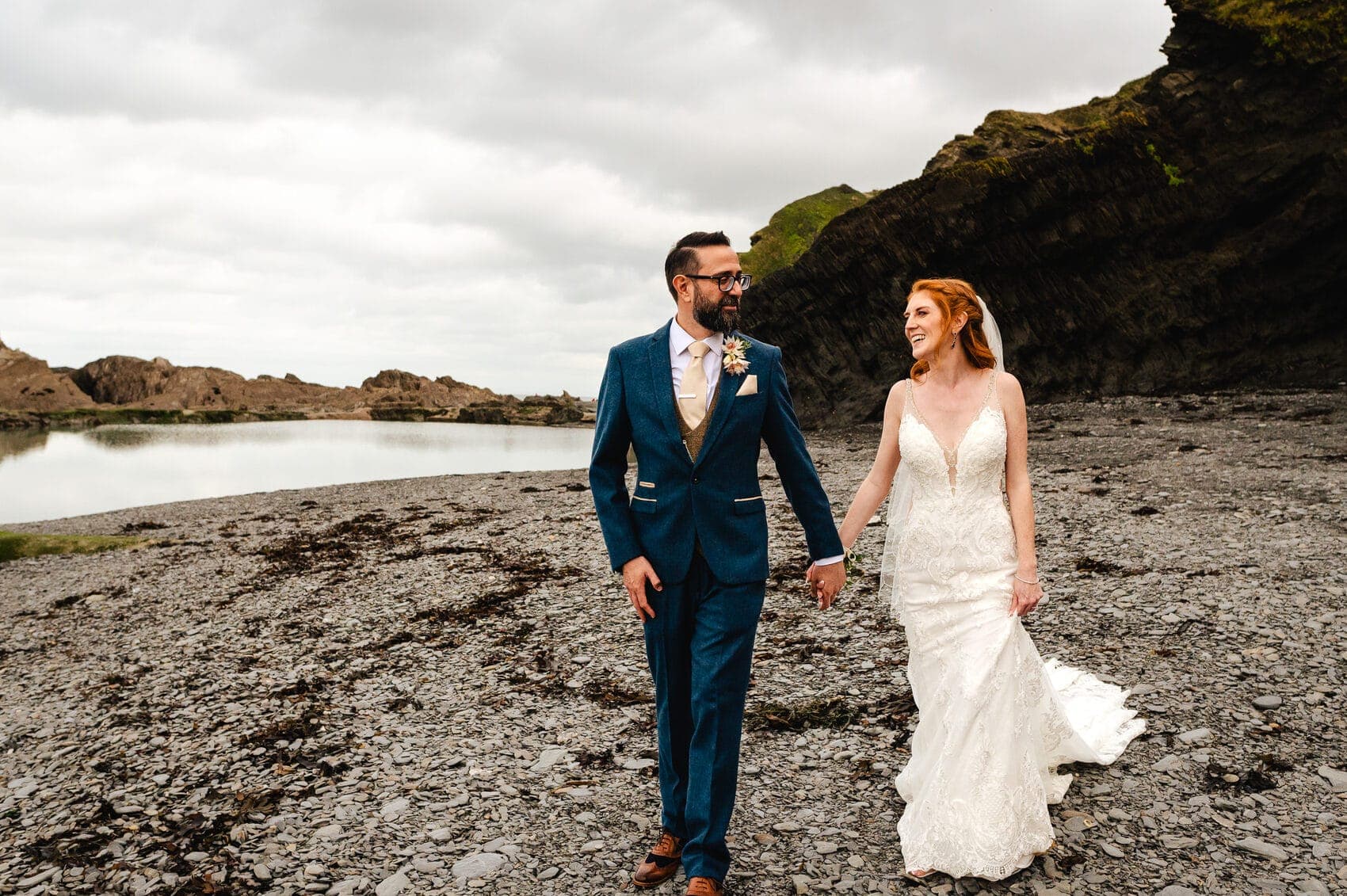 Bride and groom at Tunnels Beaches Wedding walking the beach hand in hand