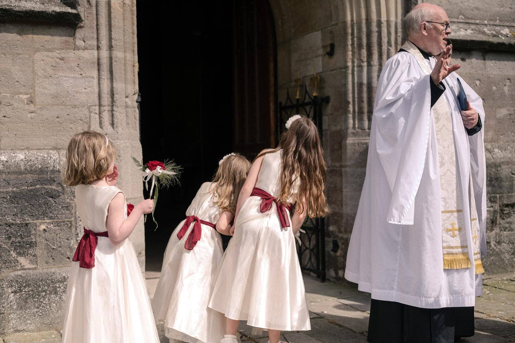 bridesmaids peek in the doorway of Christchurch Priory wedding ceremony