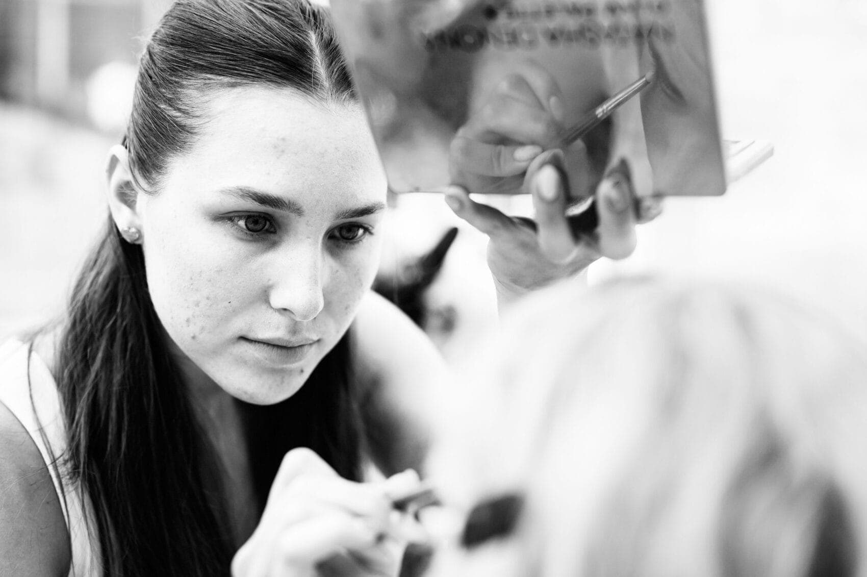 Makeup artist working on eyes showing in reflection on eyeshadow case