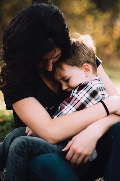 mother hugging sad little boy while solo parenting