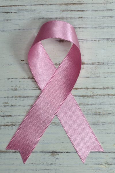 Pink breast cancer ribbon in center of a wooden surface