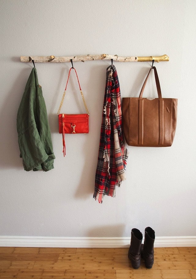 driftwood coat rack on wall with hanging coats and purses