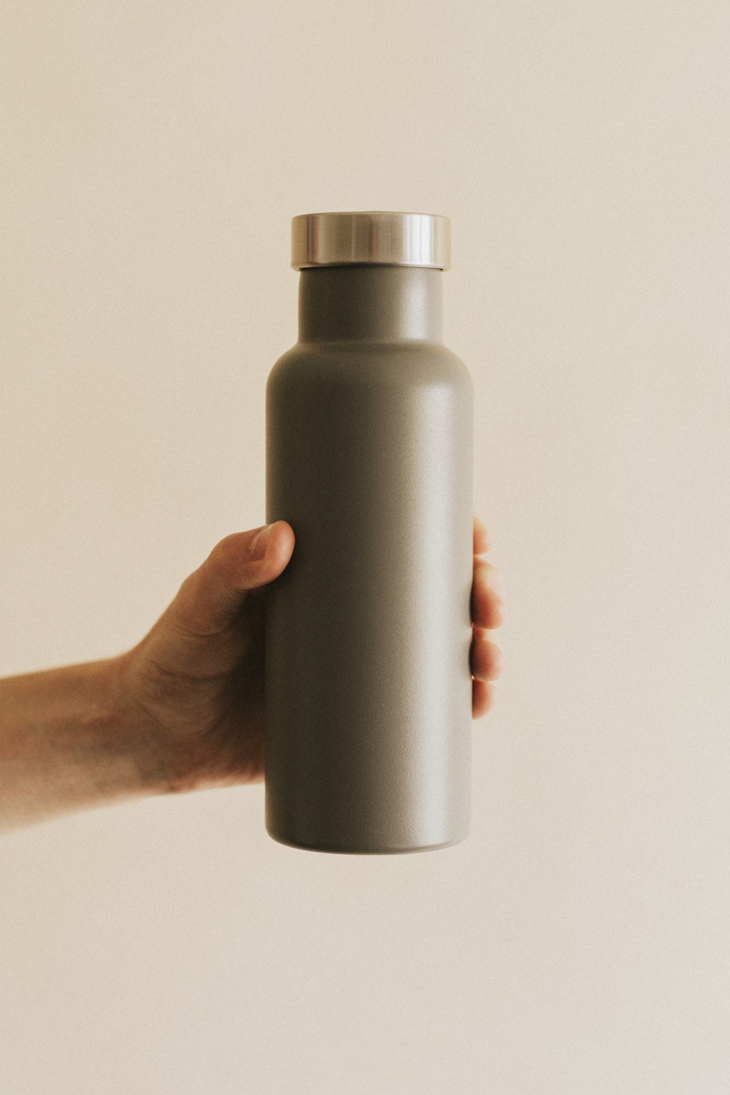 hand holding grey reusable zero-waste water bottle