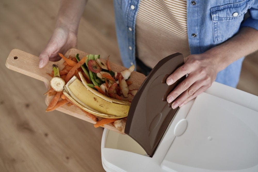 woman throwing organic waste into home kitchen compost