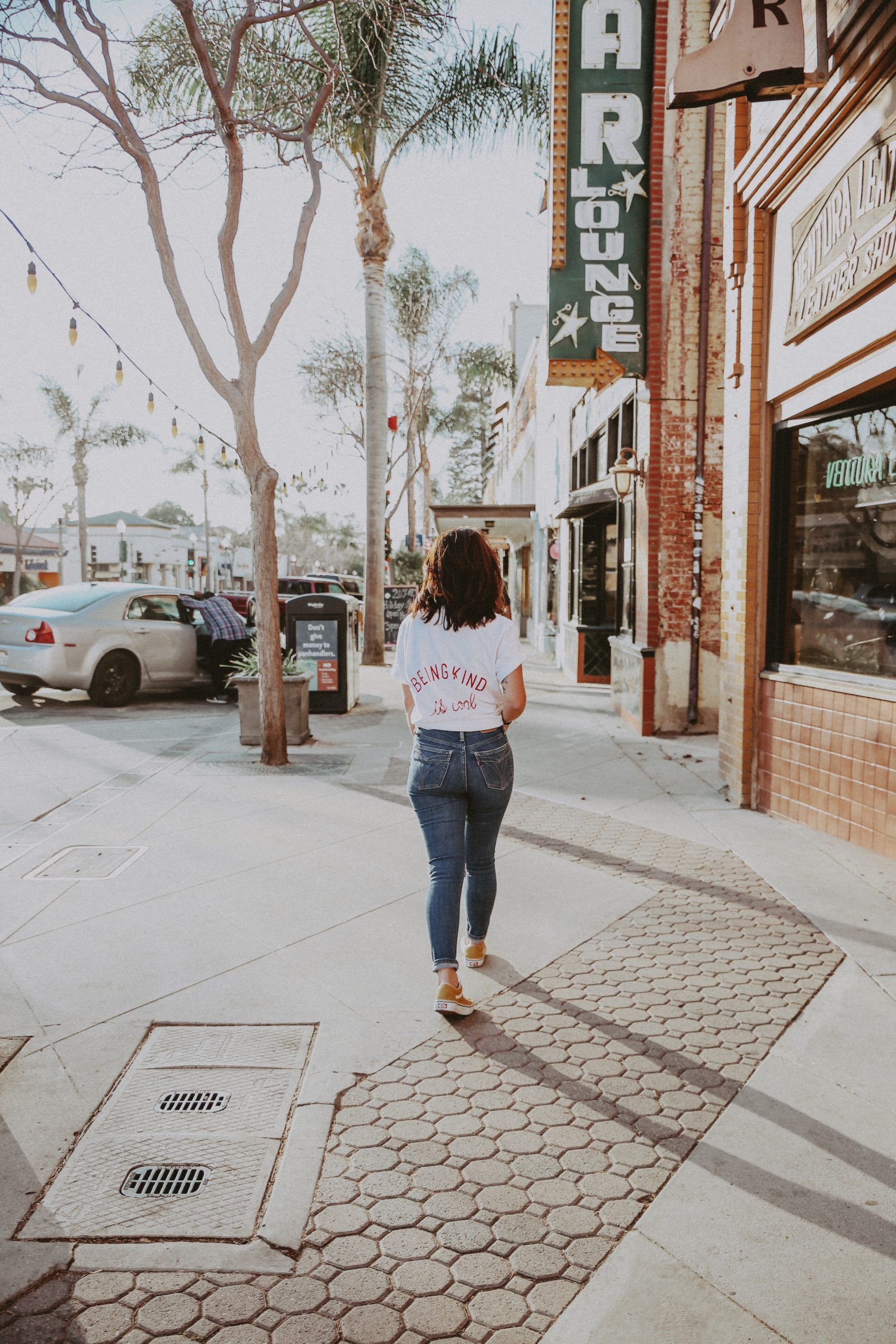 woman in t-shirt and jeans walking down street