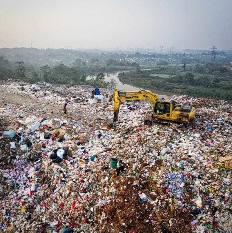 excavator pushing trash around in landfill