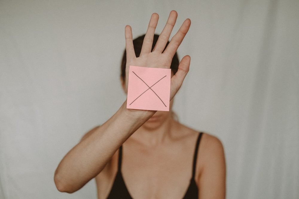 girl holding post it note with x on it