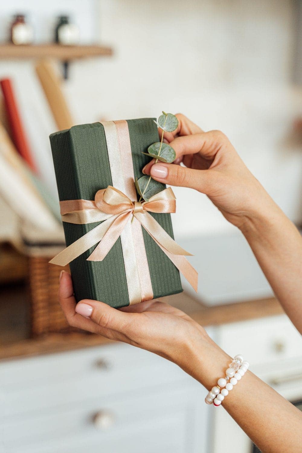 person holding gift wrapped with eco-friendly paper and fabric ribbon