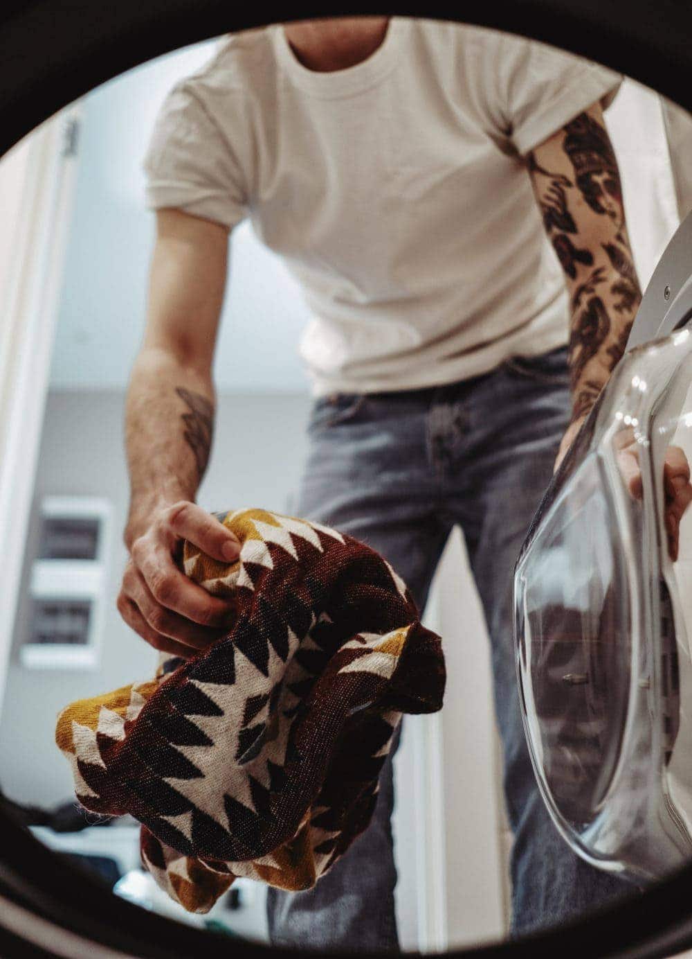 man adding clothes to laundry machine