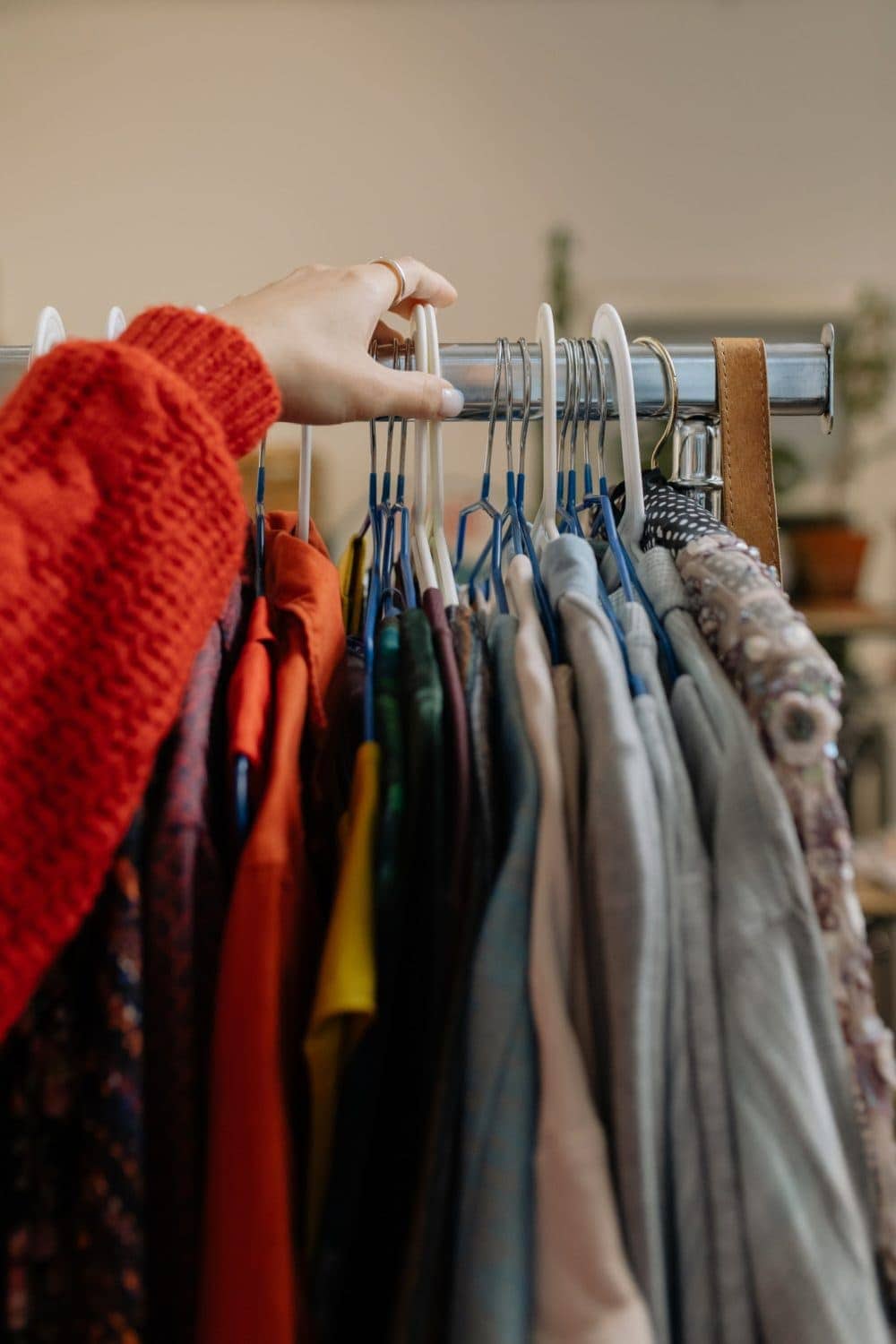 person searching through secondhand clothing rack