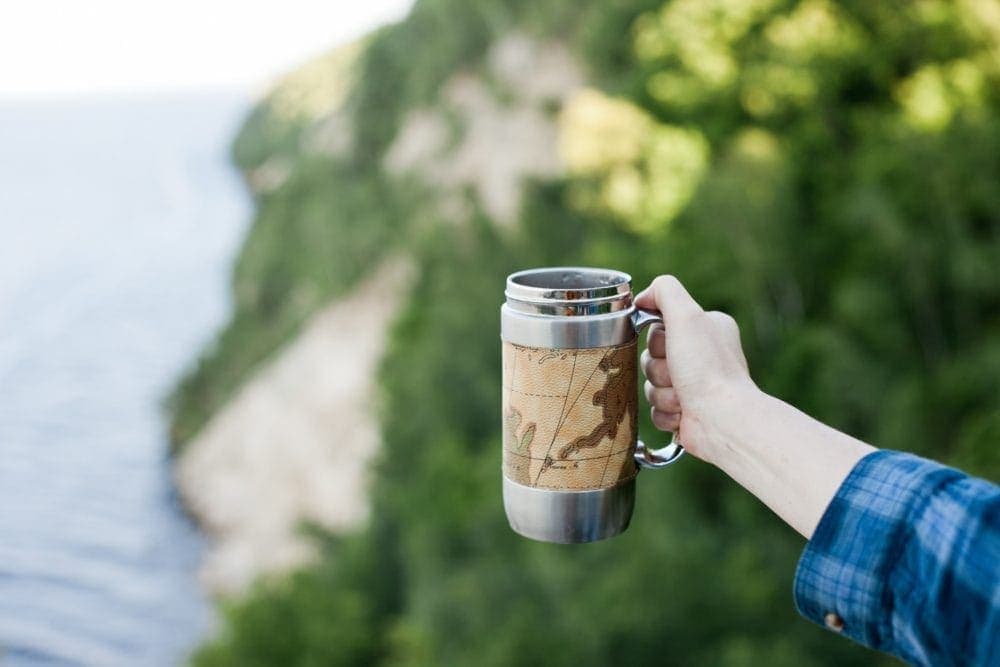 person holding reusable coffee mug 