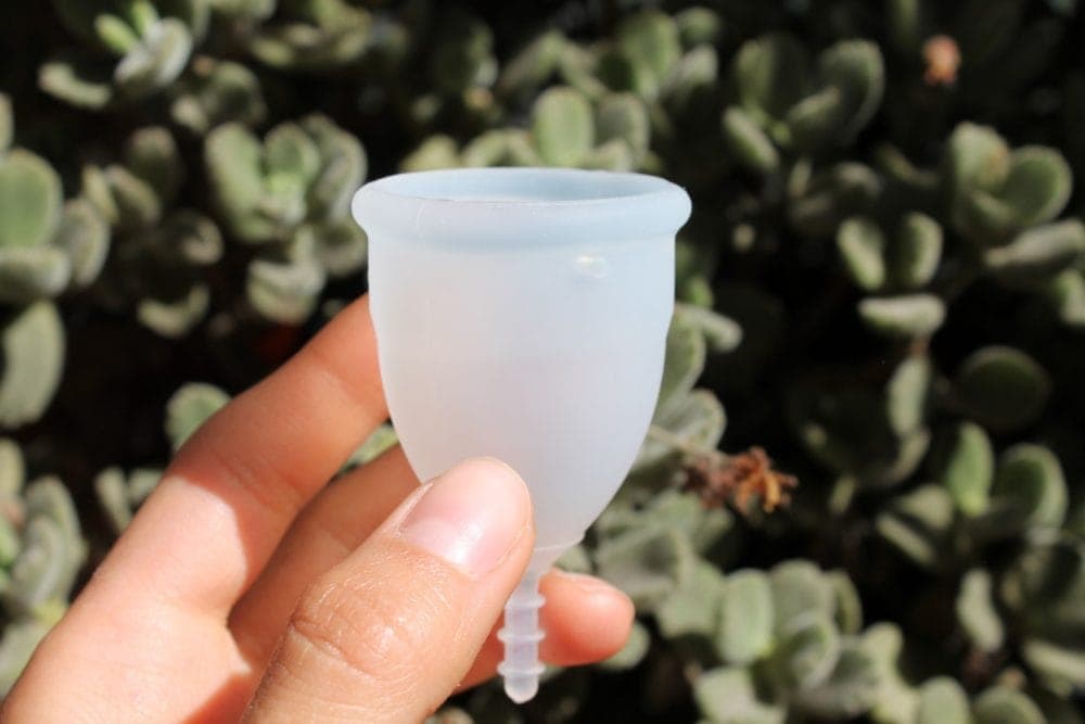 person holding empty white menstrual cup