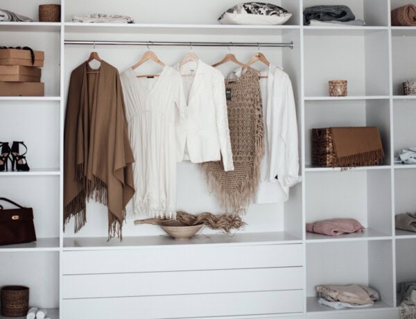 sustainable capsule wardrobe with shirts hanging, accessories and purses on shelves