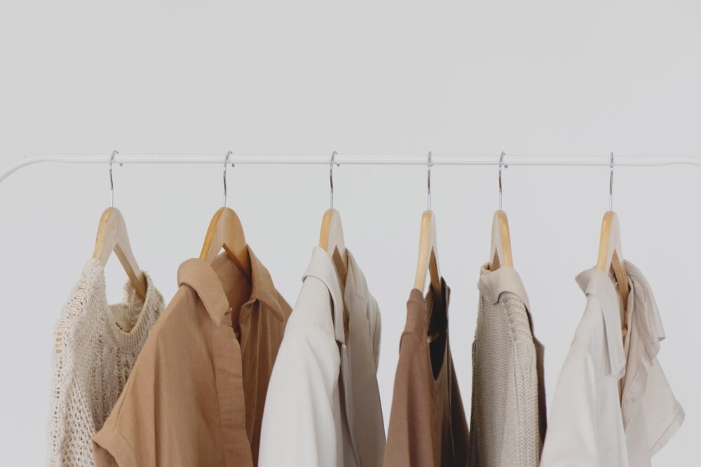 sustainable capsule wardrobe shirts on rack with beige color palette