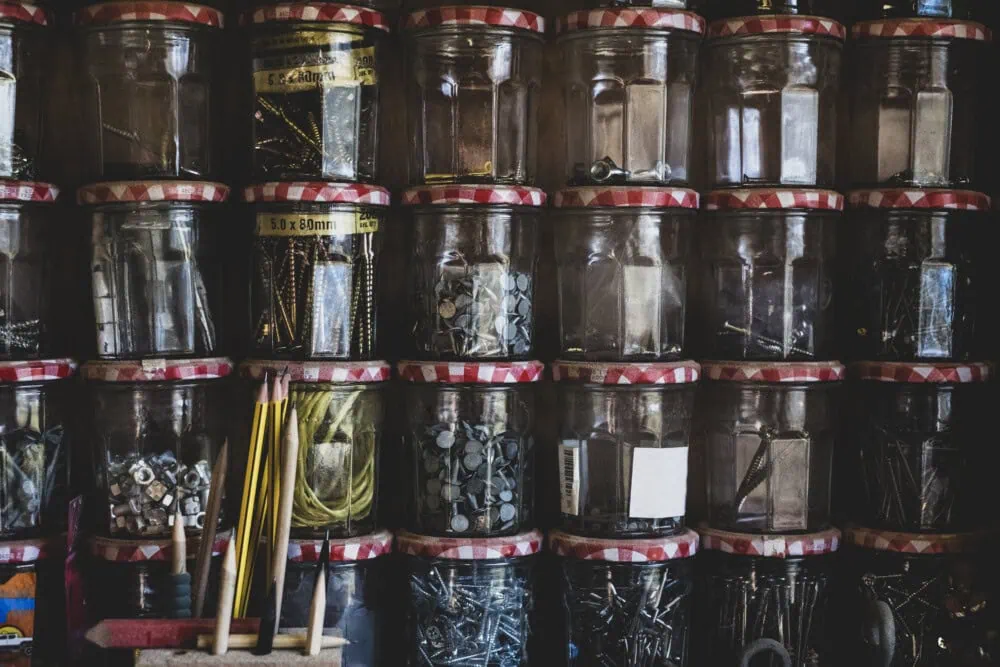 Stack of repurposed glass jam jars containing selection of nail and screws