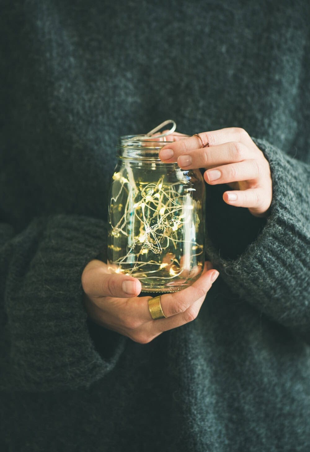 woman holding repurposed glass jar filled with fairy lights lit up