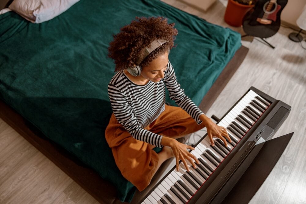 woman mindfully playing hobby piano with headphones on bed