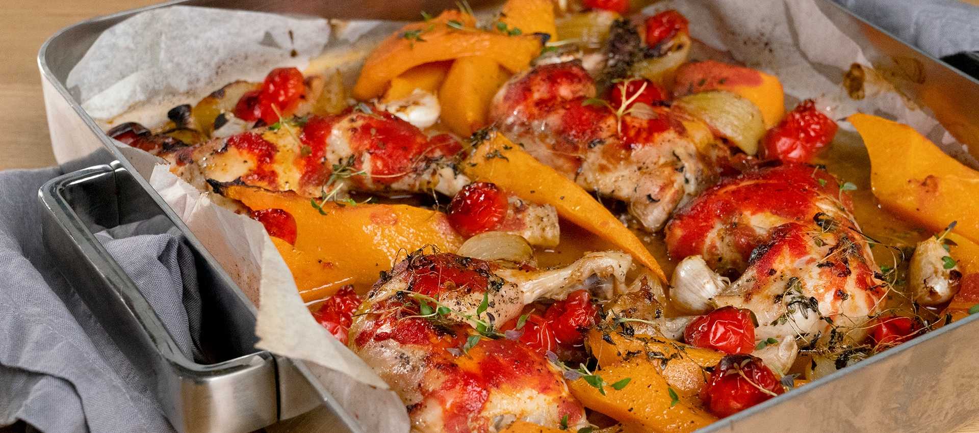 Gebackene hähnchenschenkel auf tomate und kürbis