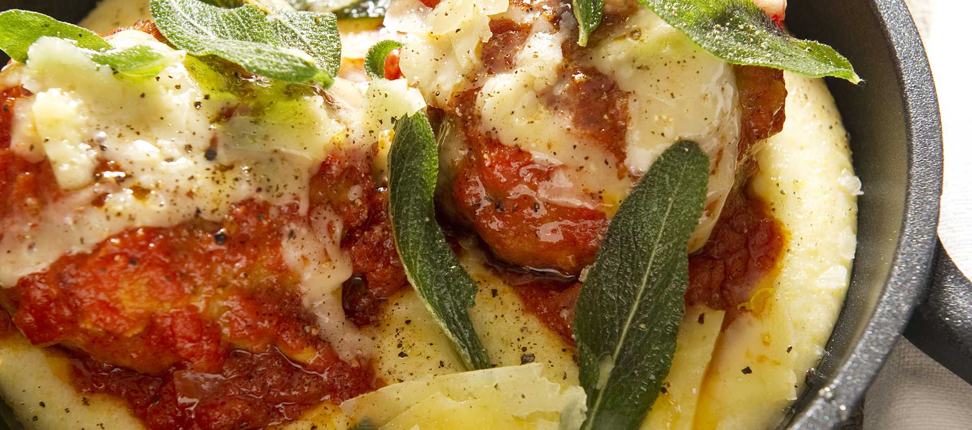 Veal meatballs in tomato sauce served with polenta and sage