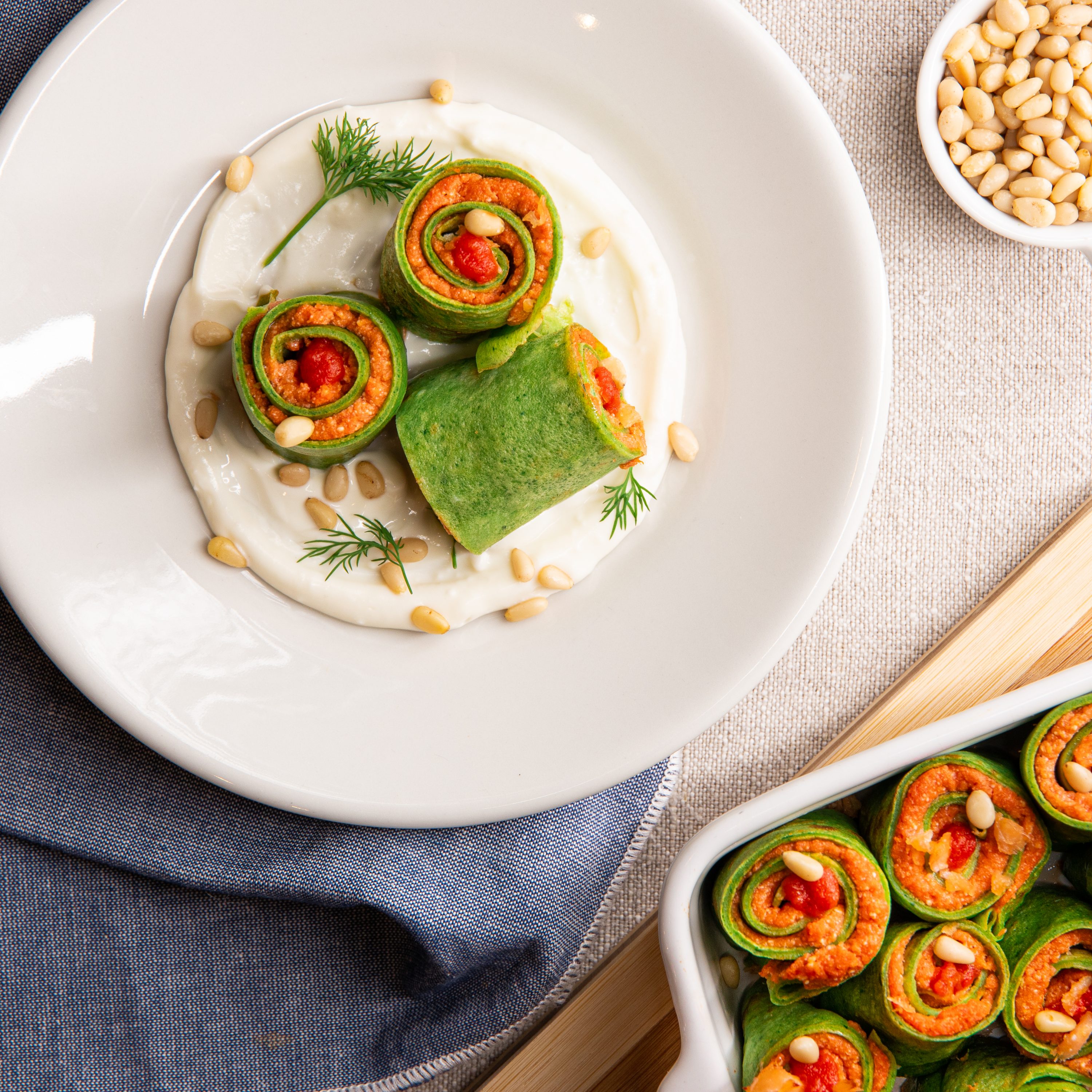 Green crepes with salmon filling and pine nuts
