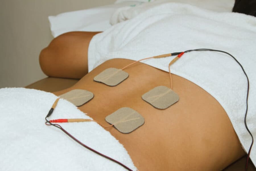 Chiropractor applying TENS therapy on a patient's shoulder for pain relief