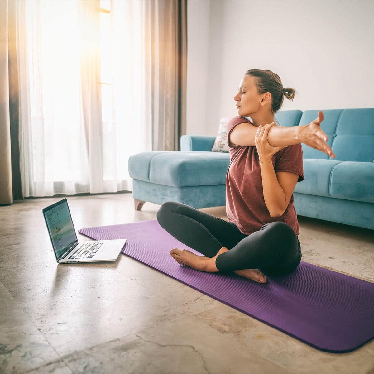 Woman practicing yoga at home via online program
