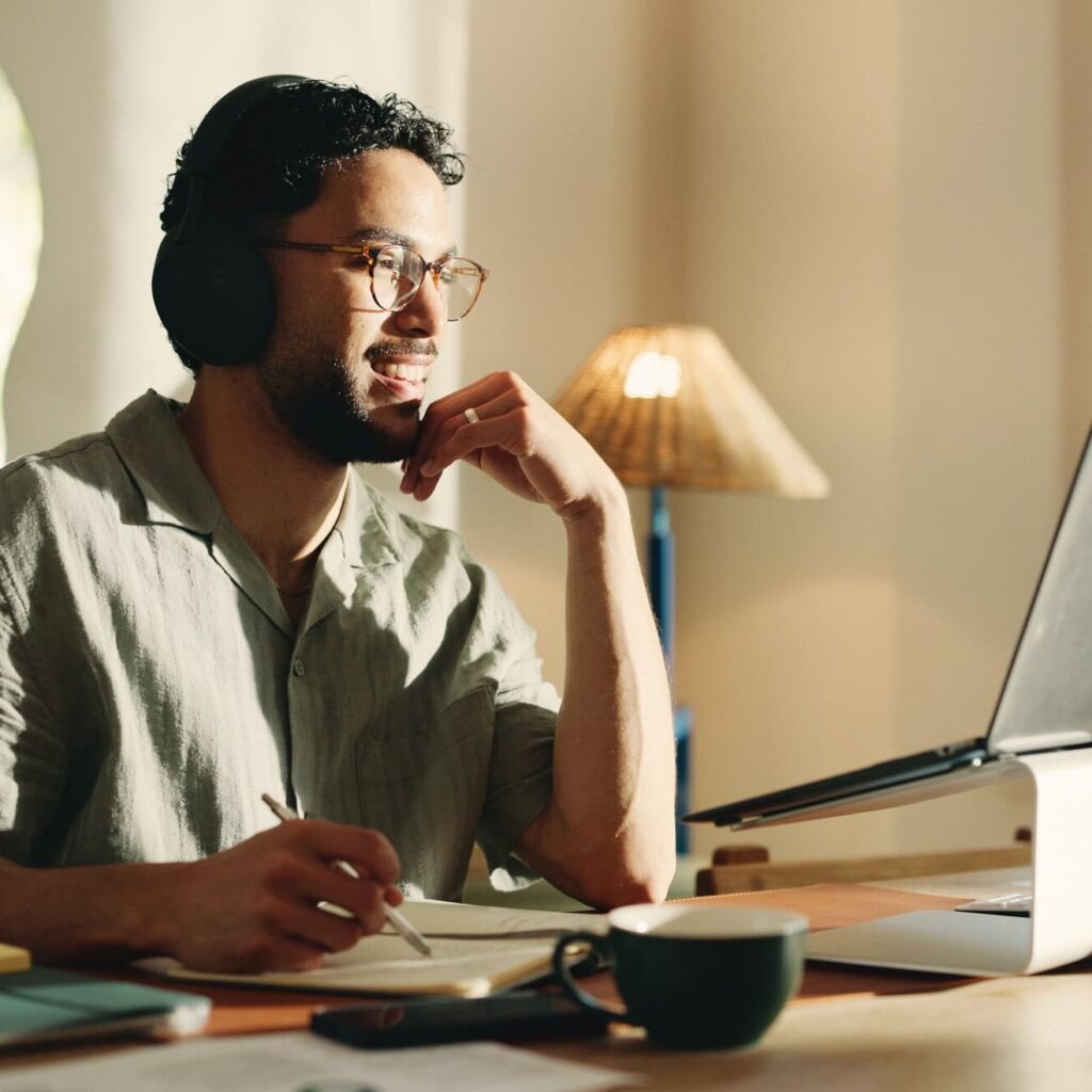 Happy, man and headphones for video, laptop and watching design tips on website, listening and home. Creative, graphic designer and person with tech for tutorial, writing and learning for remote work