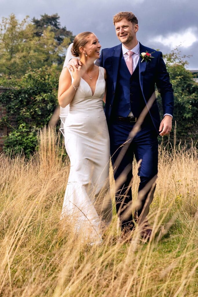 Bride and groom walking through long grass